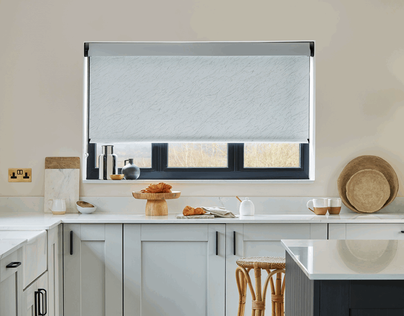 A kitchen with white cabinets and a window with a blind on it.