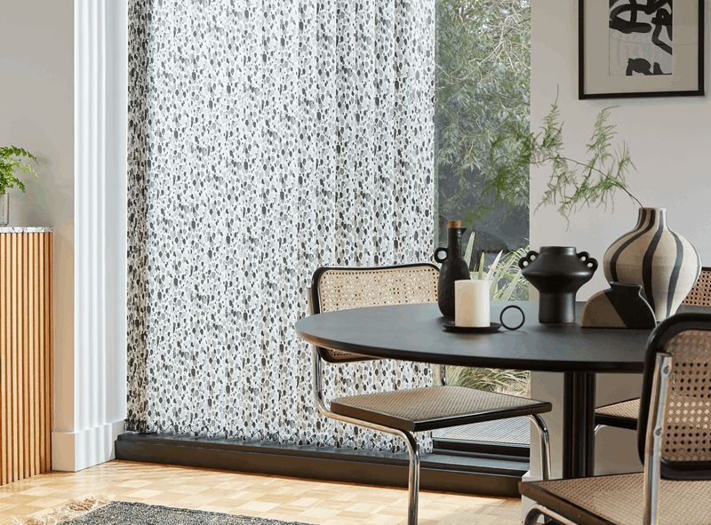 A dining room with a table and chairs and a window with blinds.