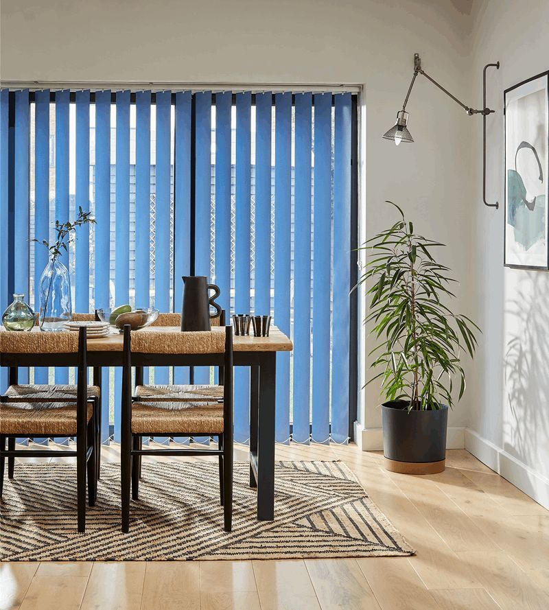 A dining room with a table and chairs and blue vertical blinds