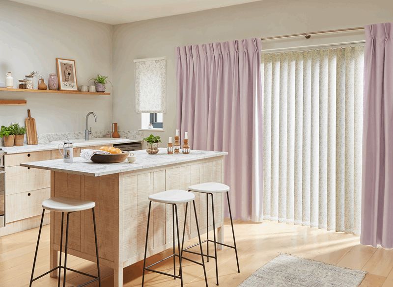 A kitchen with a large island and stools and purple curtains.