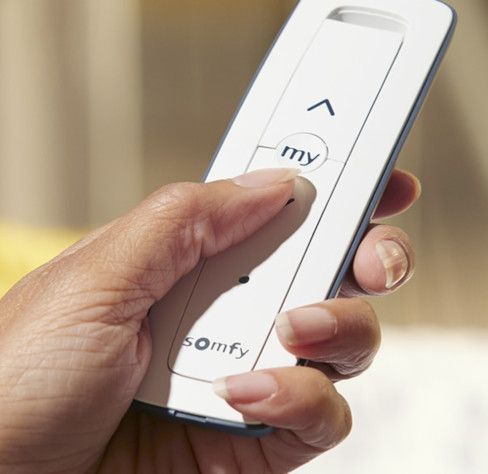 A person is holding a somfy remote control in their hand.