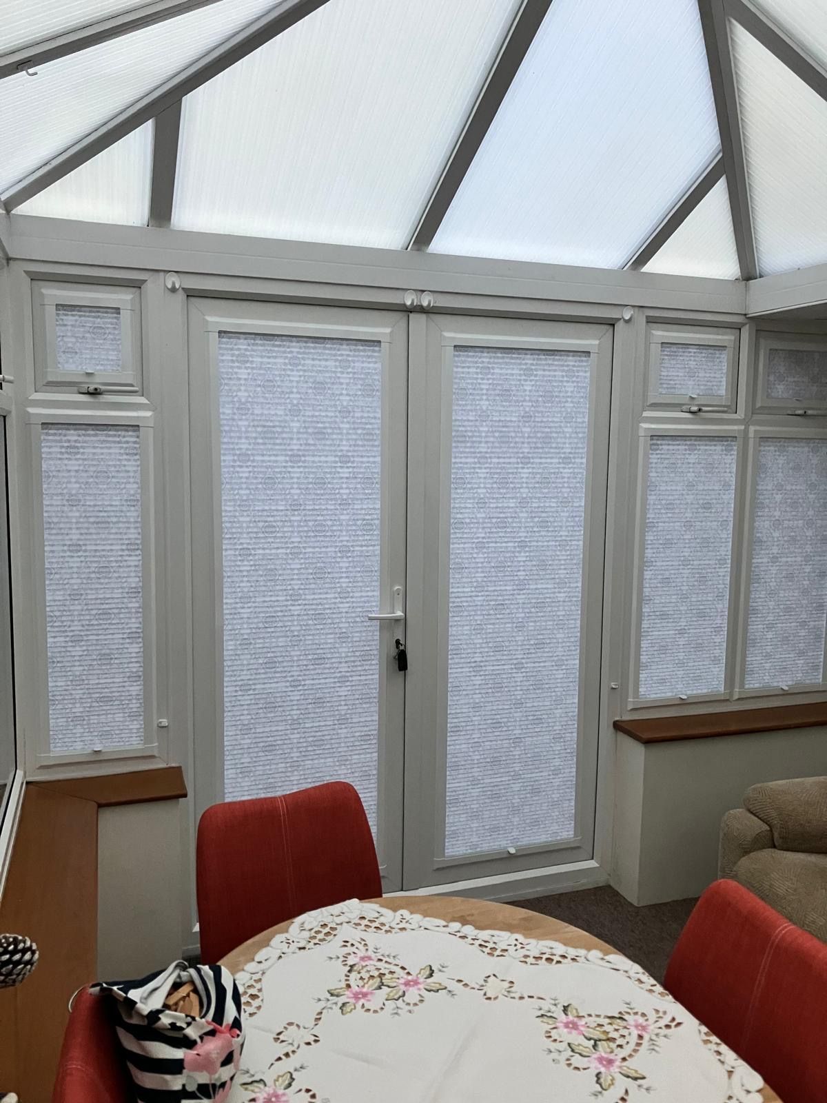 A dining room with a table and chairs in a conservatory.