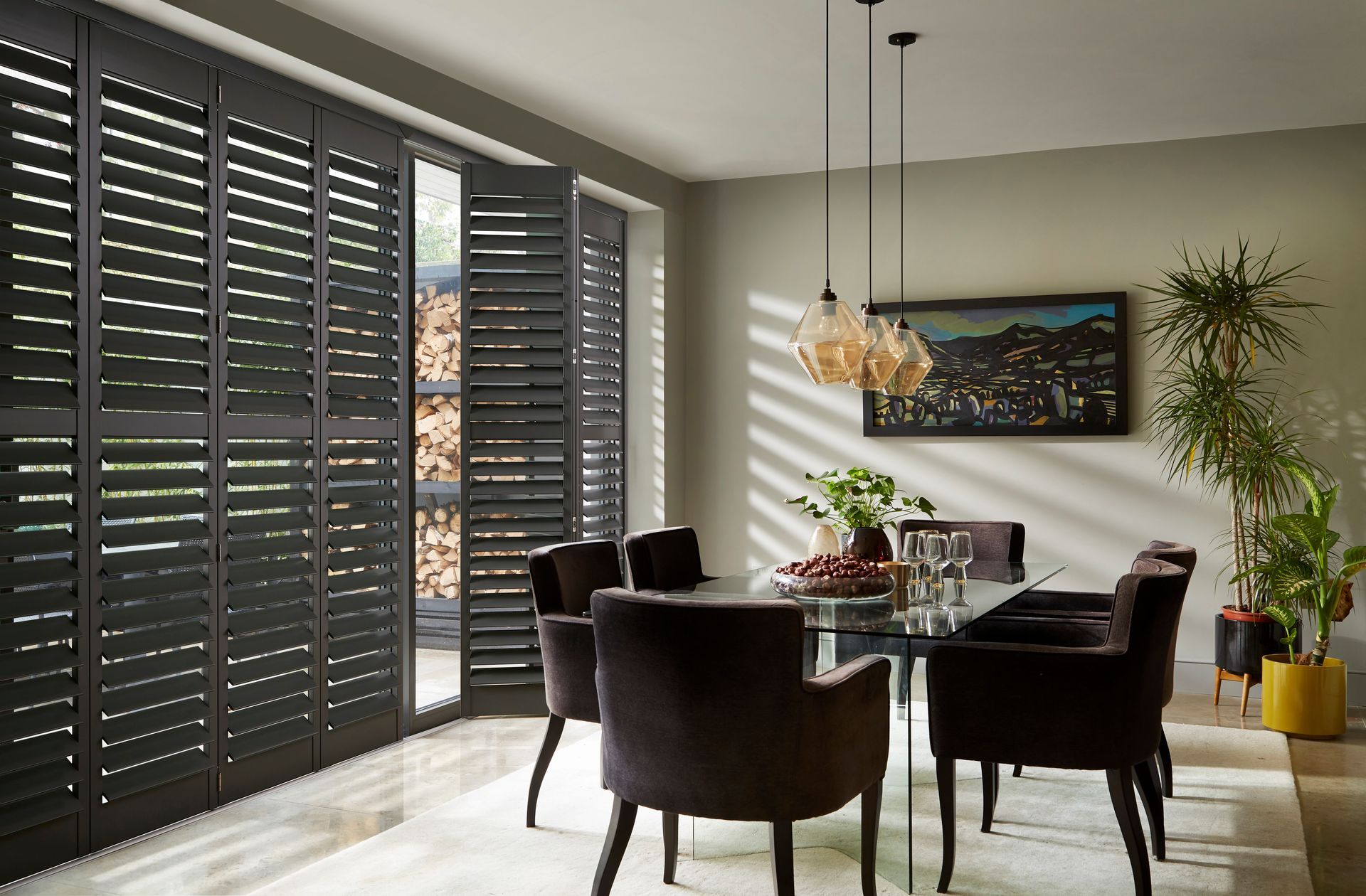 A dining room with a table and chairs and black shutters