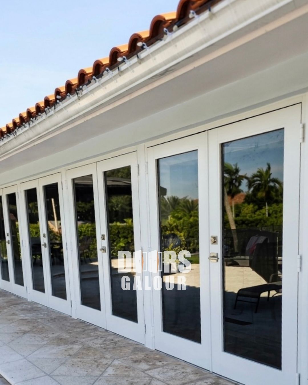 Wooden double doors with glass panels and black handles set in a white doorframe on a brick step.