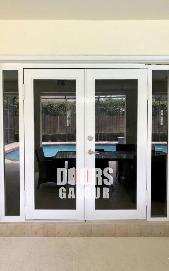 Wooden double doors with glass panels and black handles set in a white doorframe on a brick step.