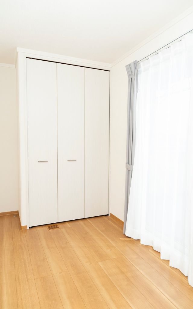 Two white closet doors, and a doorway. Beige walls and a ceiling fan.