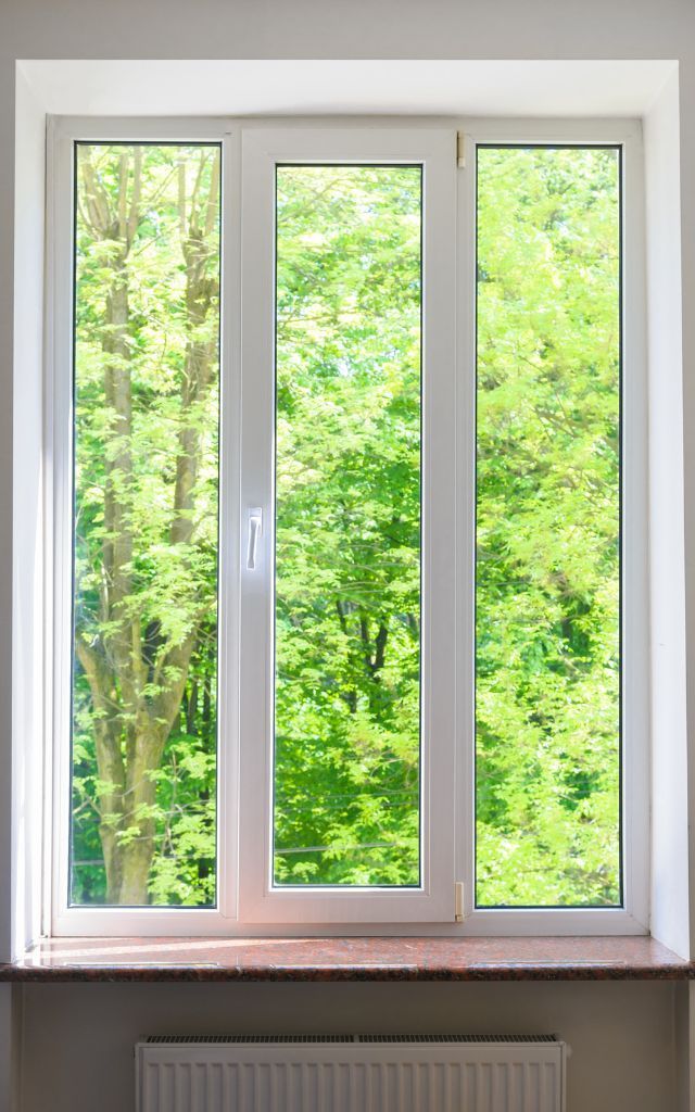 Newly installed window in a concrete wall, with unfinished stucco surrounding it.