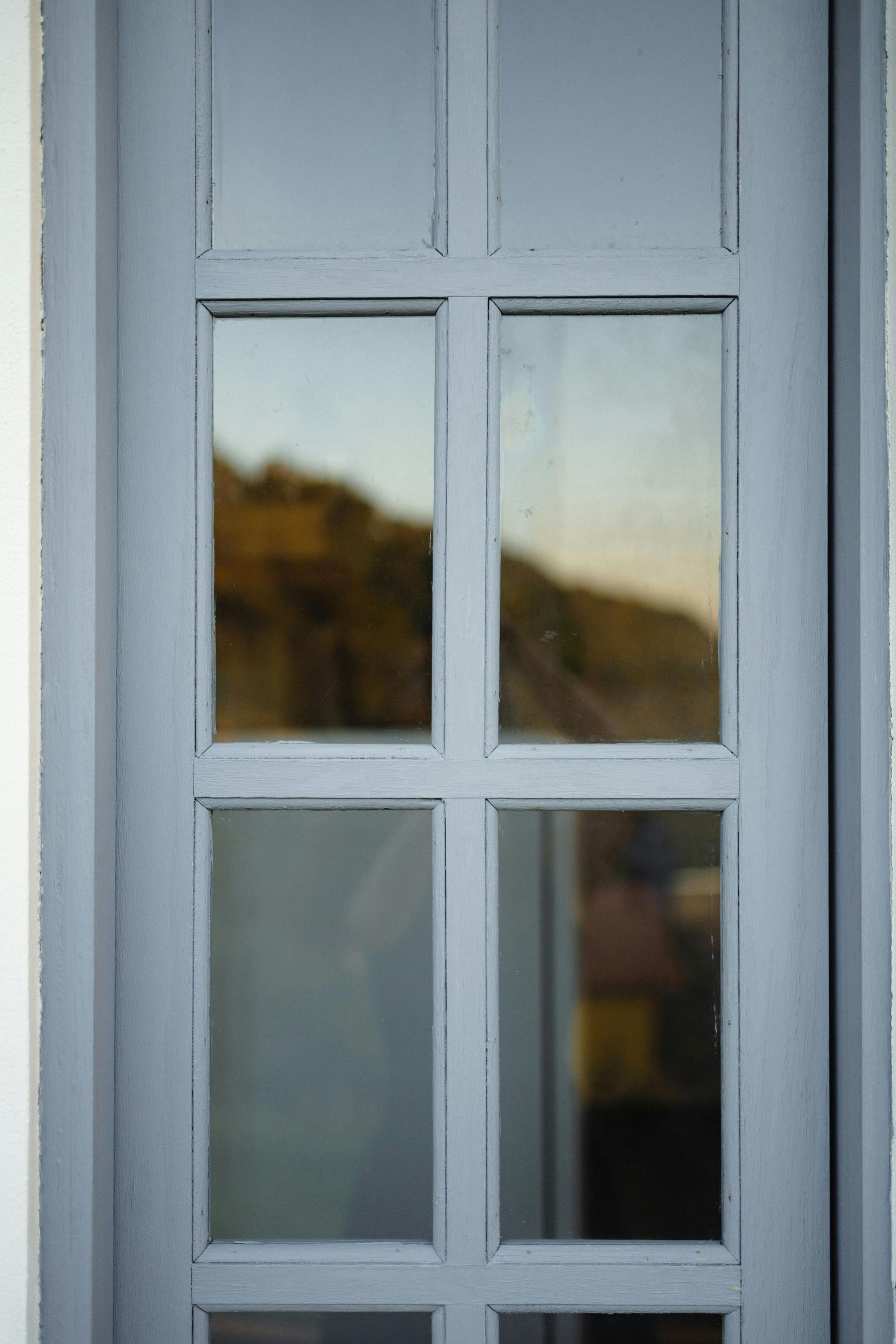 Sunlight through a window, illuminating white walls and a wooden frame against a blue sky.