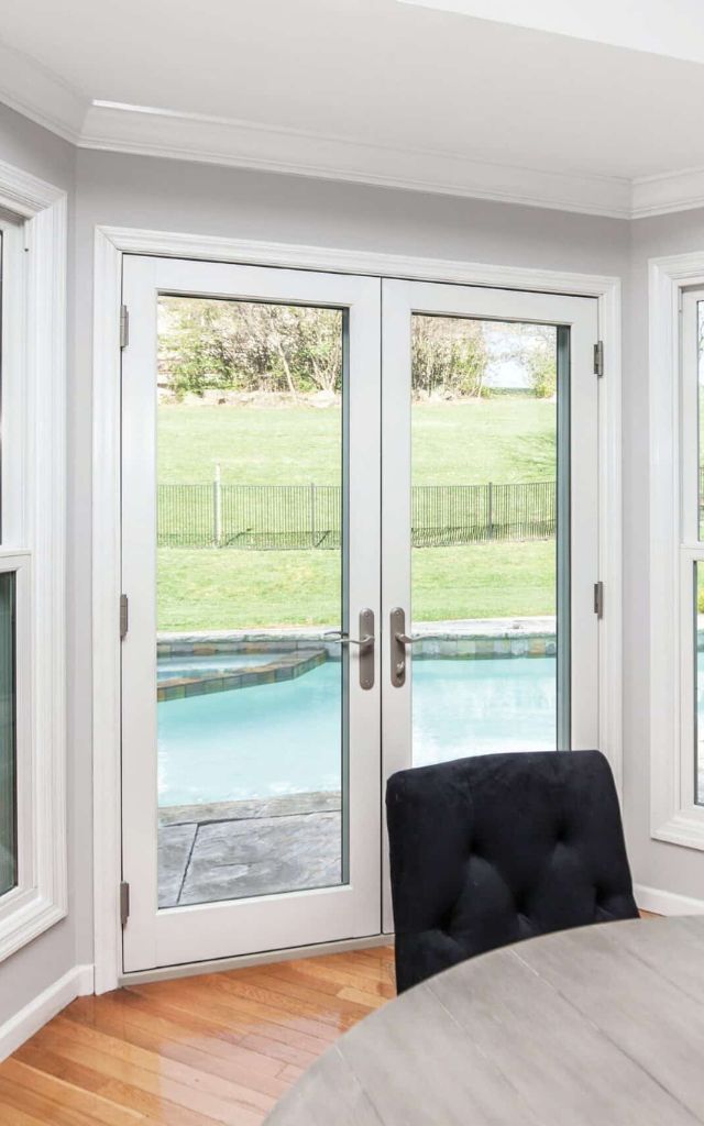 White double front doors with rectangular frosted glass panels and long silver handles.
