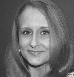 A woman with long hair is smiling in a black and white photo.