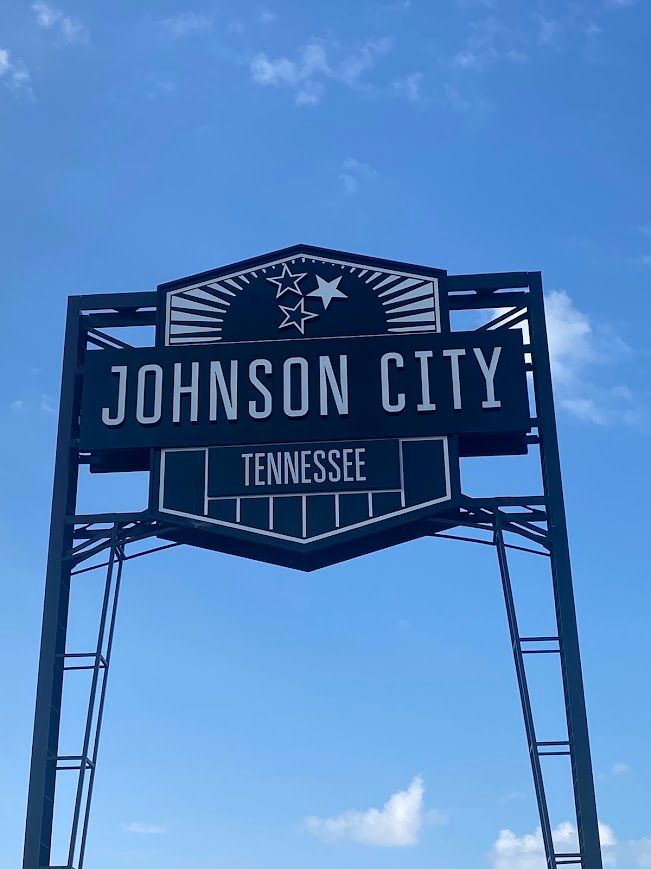 A sign for johnson city tennessee against a blue sky