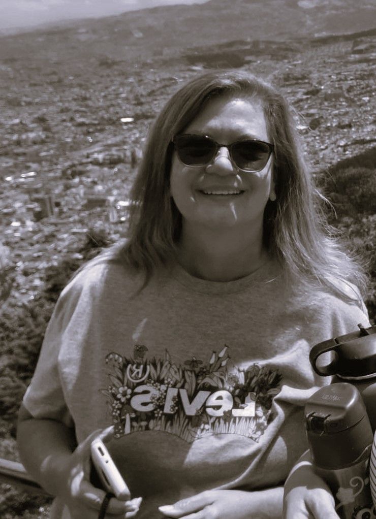 A woman wearing sunglasses and a shirt that says harvest is smiling in a black and white photo.