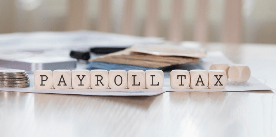 The word payroll tax is written on wooden blocks on a table.