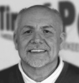 A man with a beard is smiling in a black and white photo.