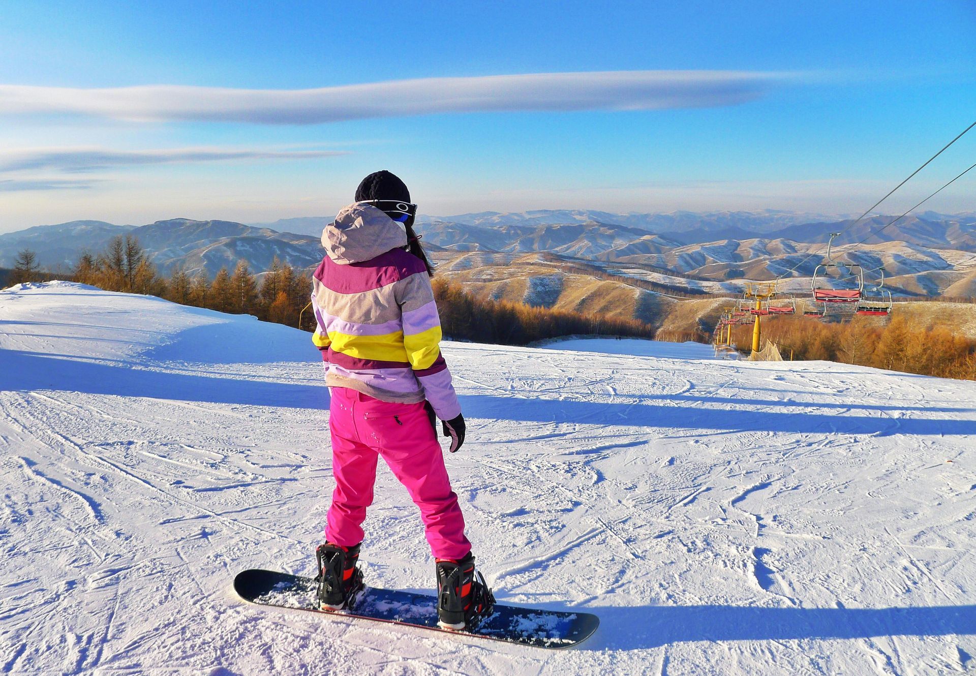 A person is standing on a snowboard on top of a snow covered slope.