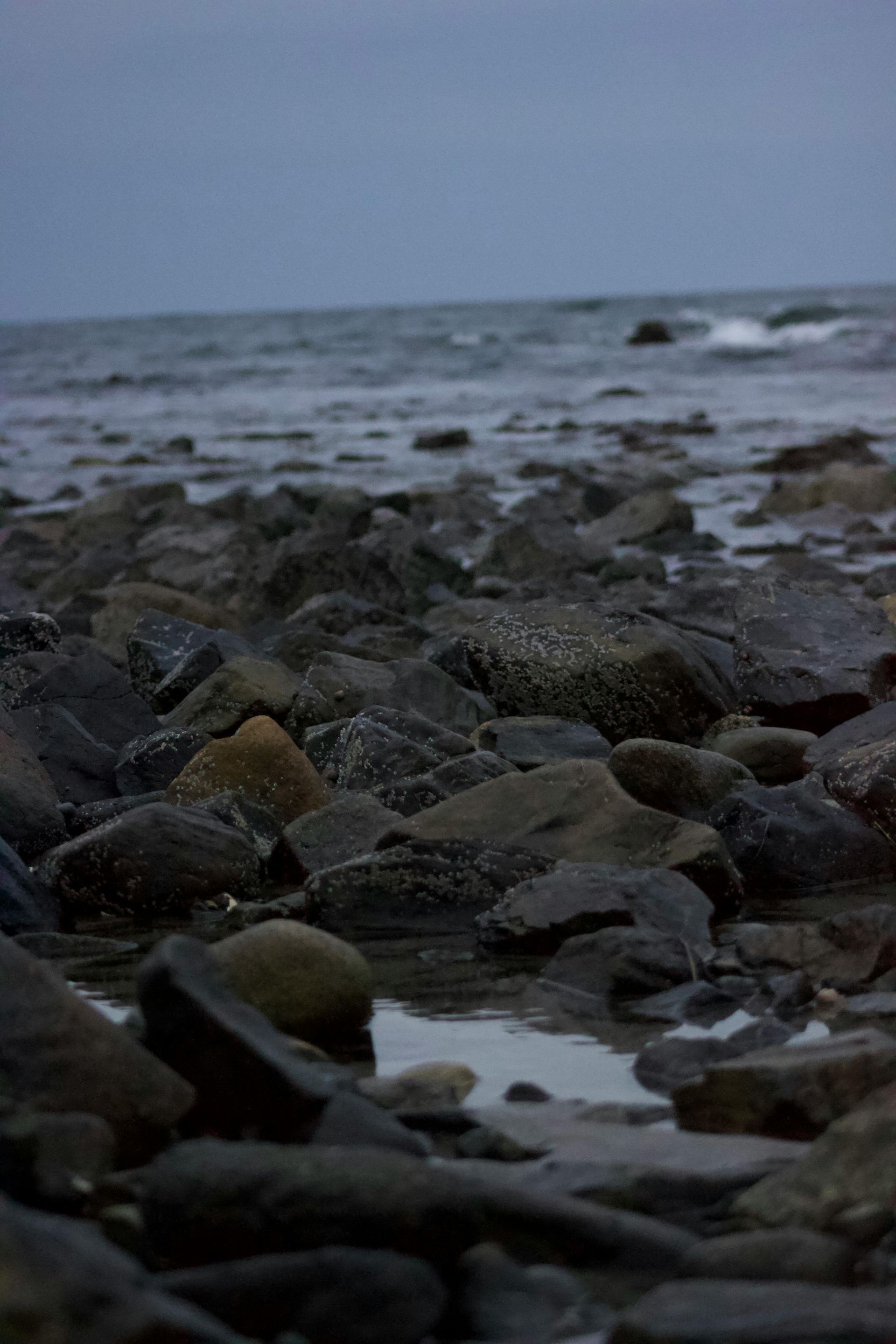 A rocky beach with a body of water in the background.