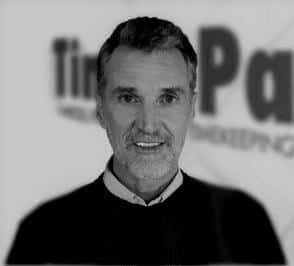 A man with a beard is smiling in a black and white photo.