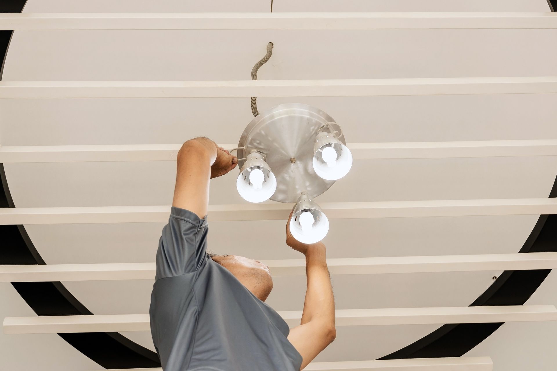 A man is fixing a light fixture on the ceiling.