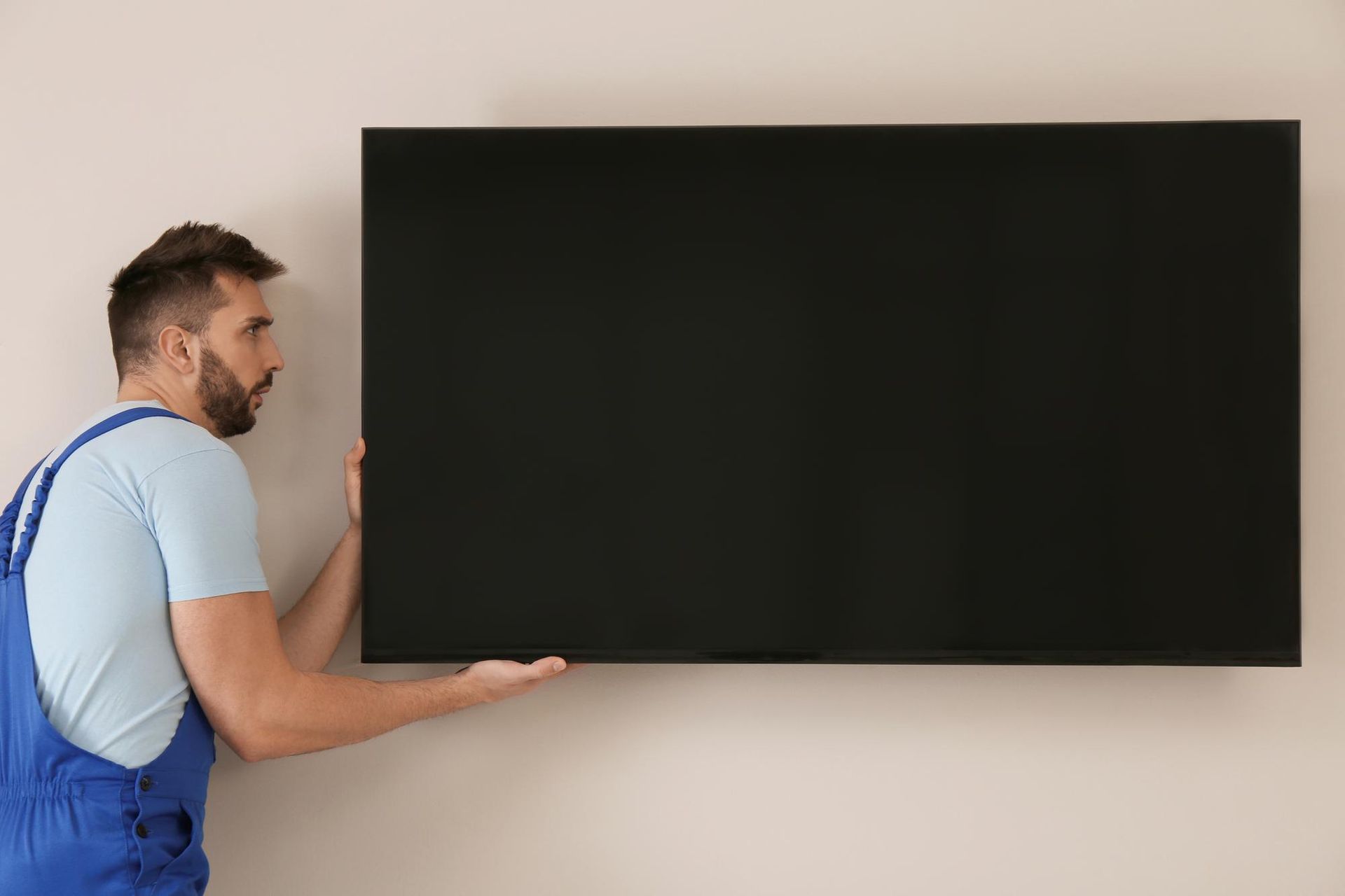 A man is installing a flat screen tv on a wall.
