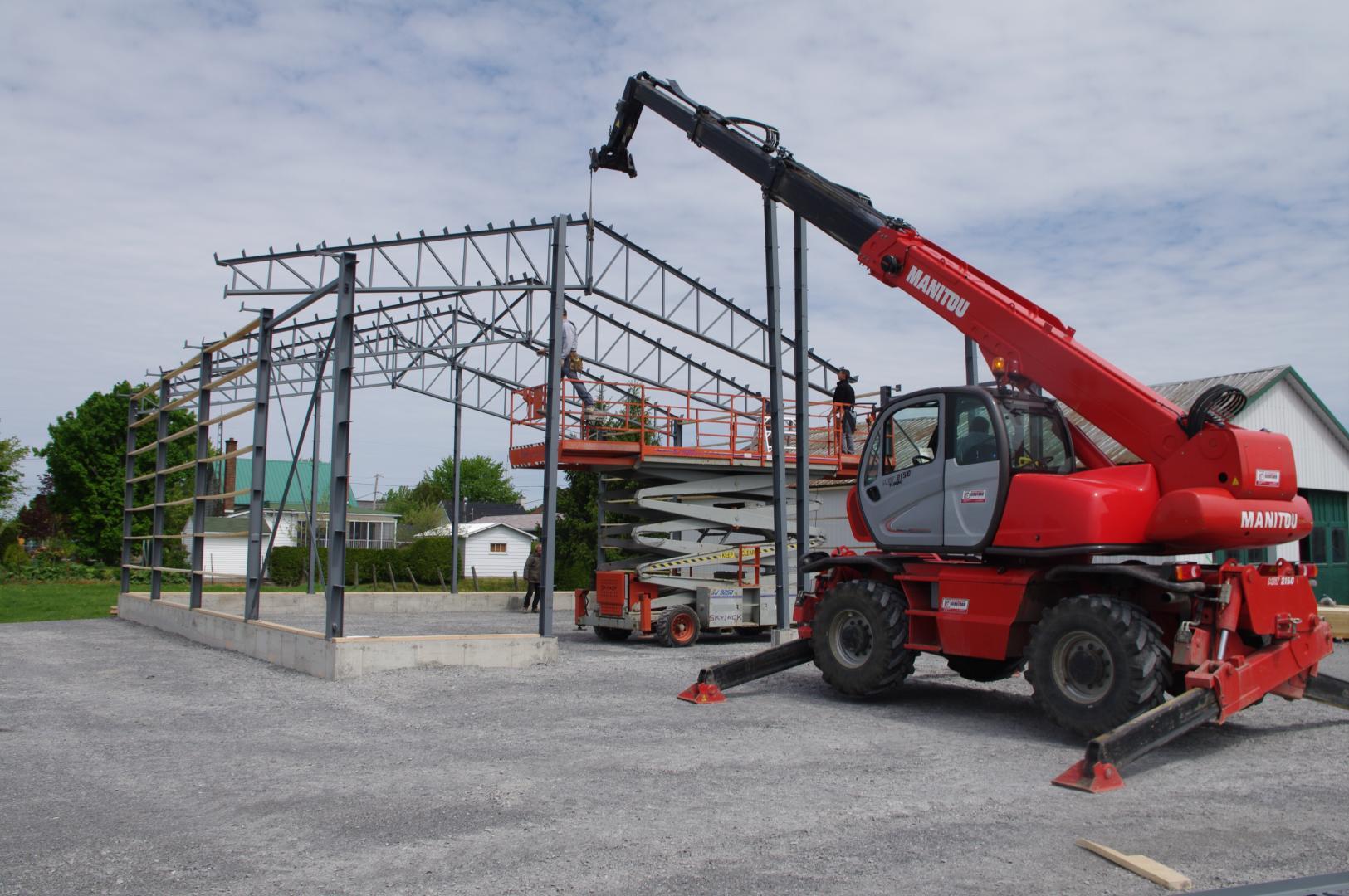 Une grue rouge est assise devant un bâtiment en construction