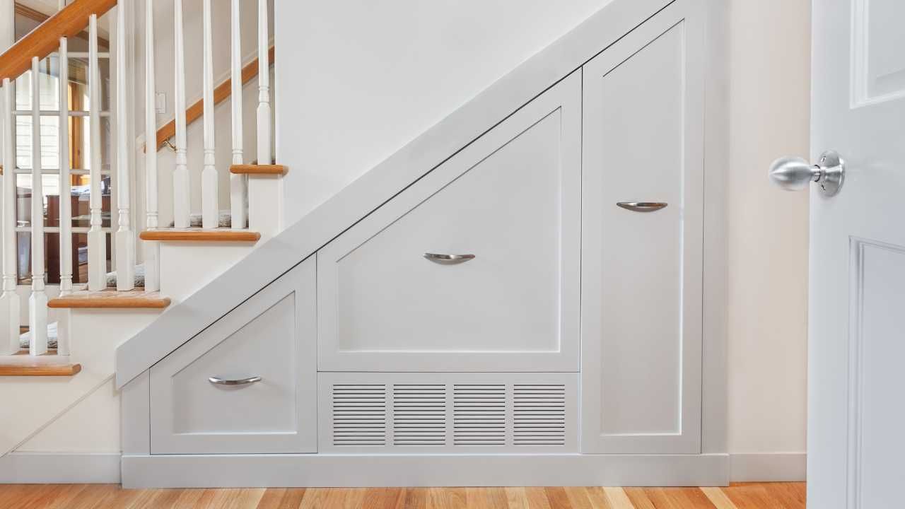 A white staircase featuring a built-in storage unit.