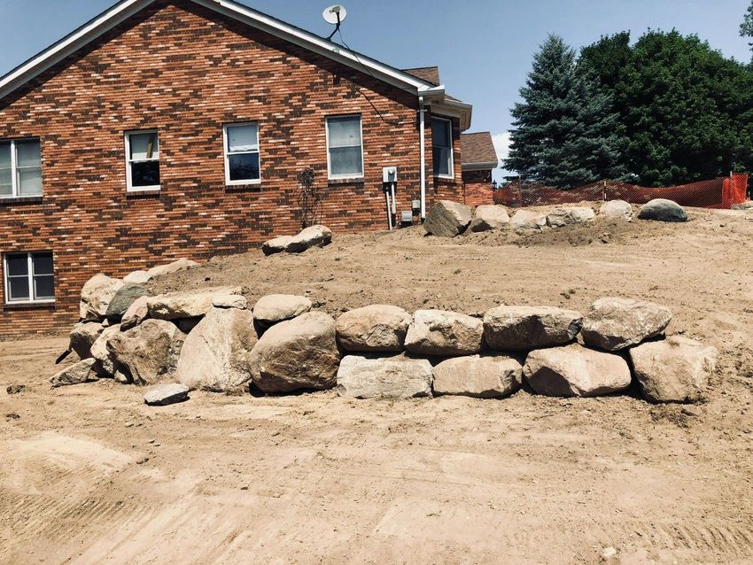Brick house with a stone retaining wall on a dirt slope under construction