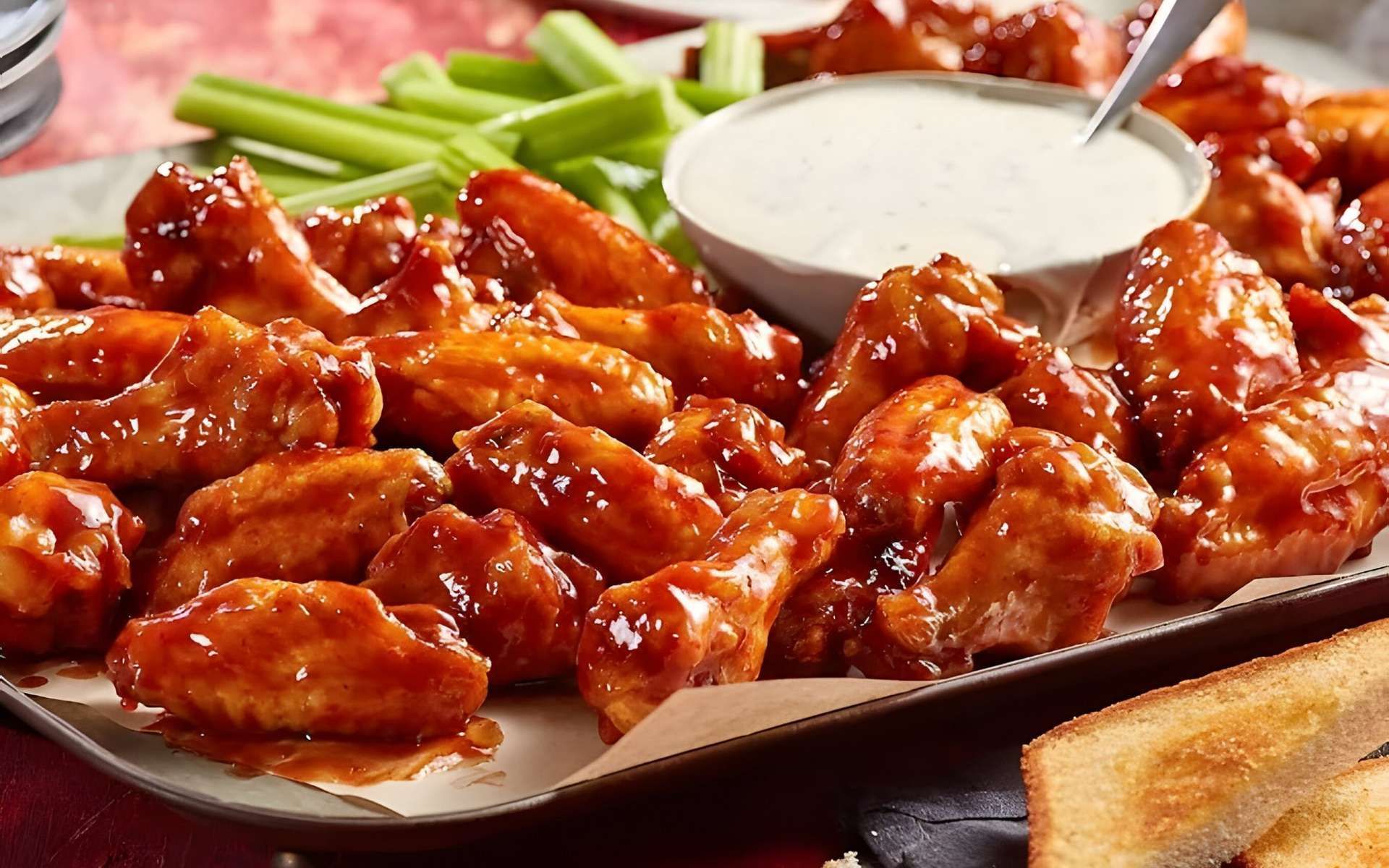 Buffalo chicken wings with celery sticks and ranch dip on a serving tray