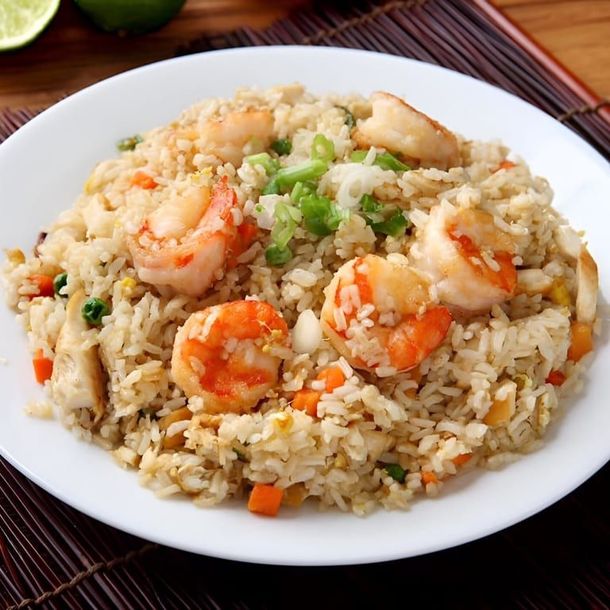 Shrimp fried rice on a white plate with green onions and diced vegetables