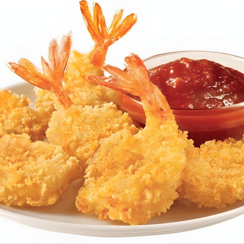 Golden breaded shrimp with a side of red dipping sauce on a white plate
