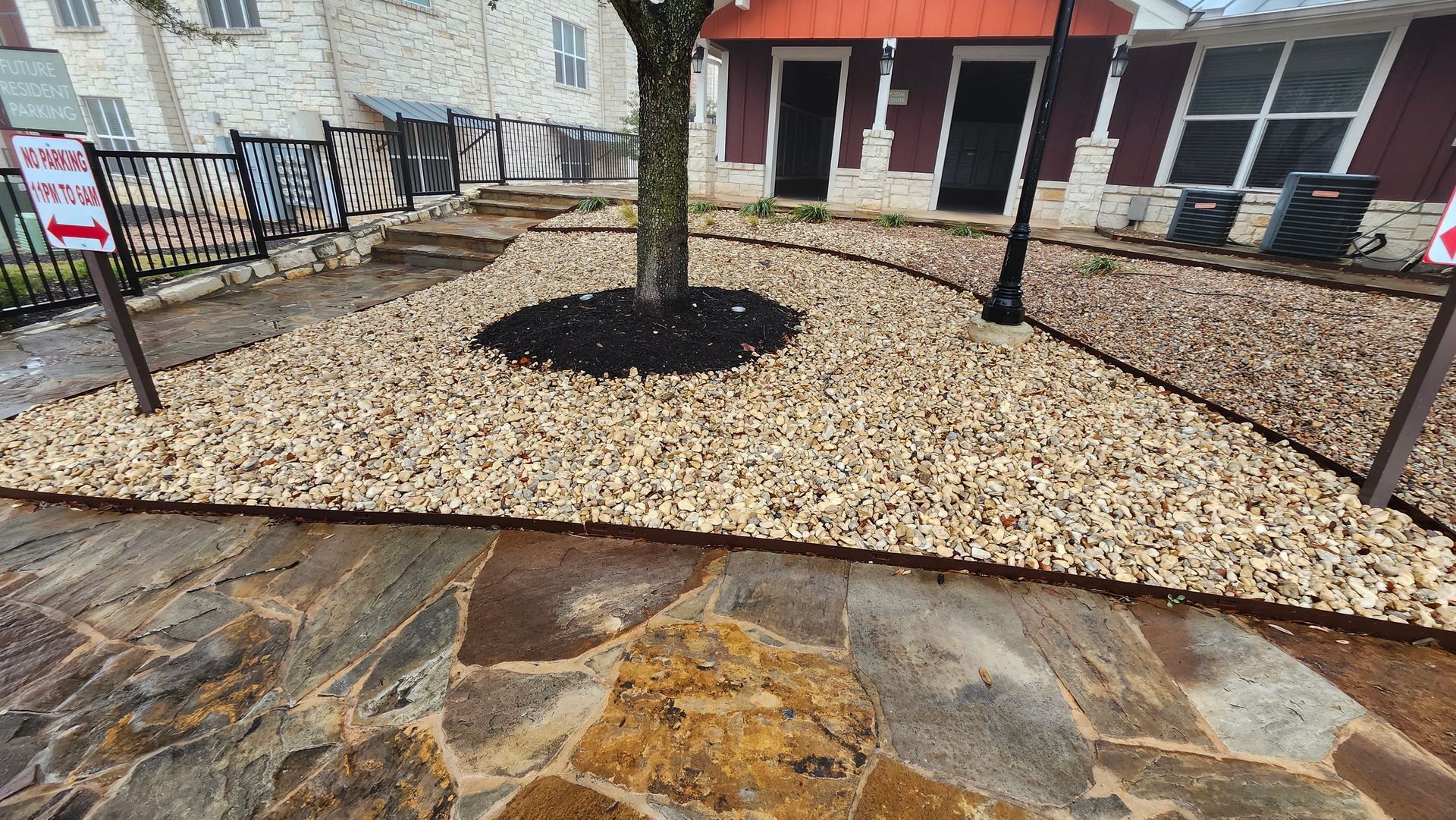 Flagstone path leads to a building entrance with tan gravel landscaping.