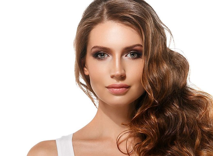 A woman with long brown hair is wearing a white tank top.