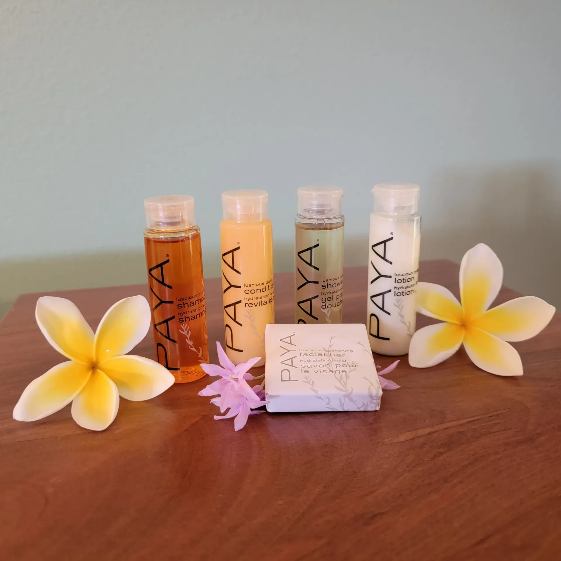 Four bottles of paya cosmetics are on a wooden table