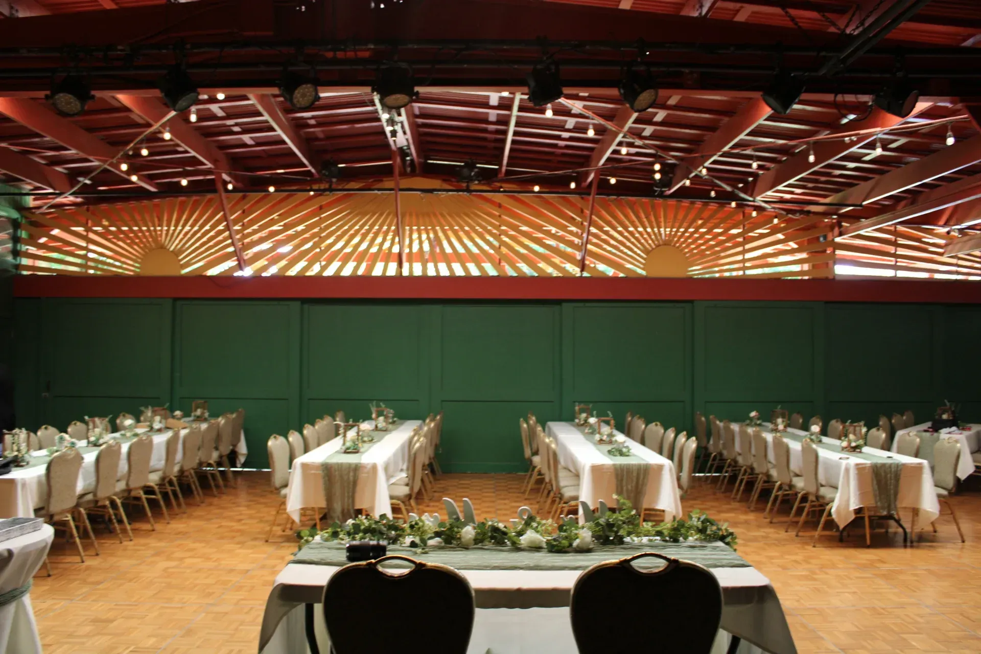 A large room with tables and chairs set up for a wedding reception