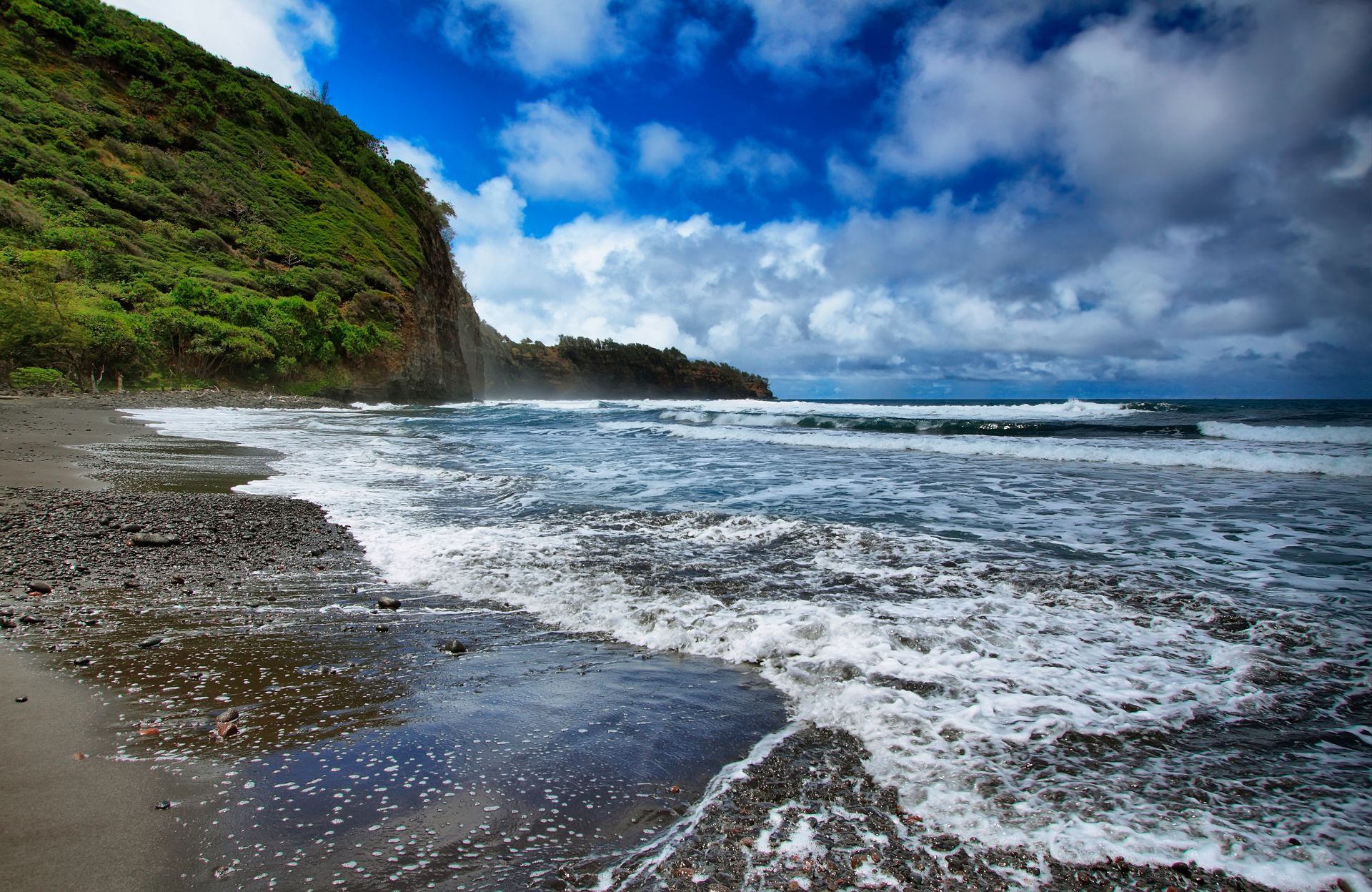 A beach with waves crashing on the shore on a cloudy day