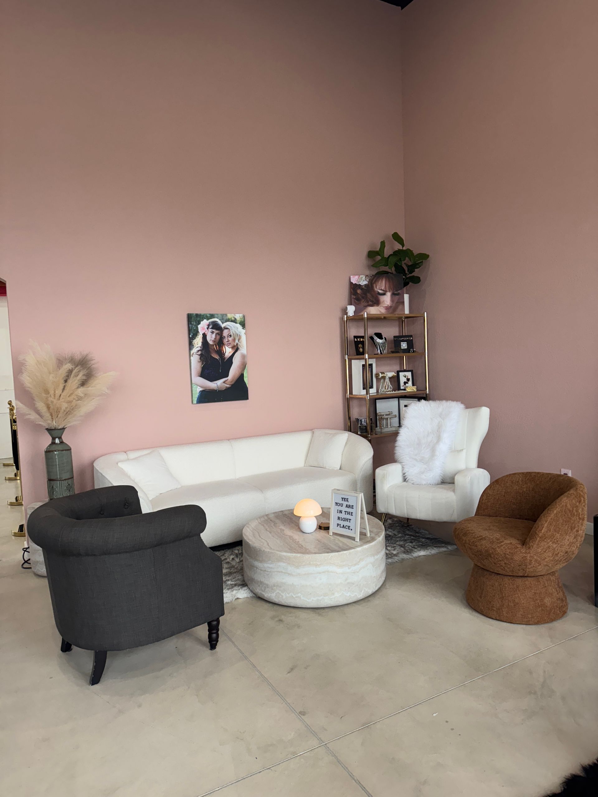 Living room with a white couch, chairs, and decorative items against a pink wall.