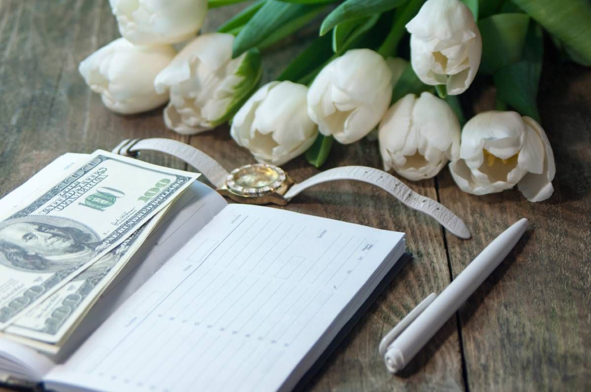 Funeral flowers with planner, pen, and money symbolizing transparent costs.