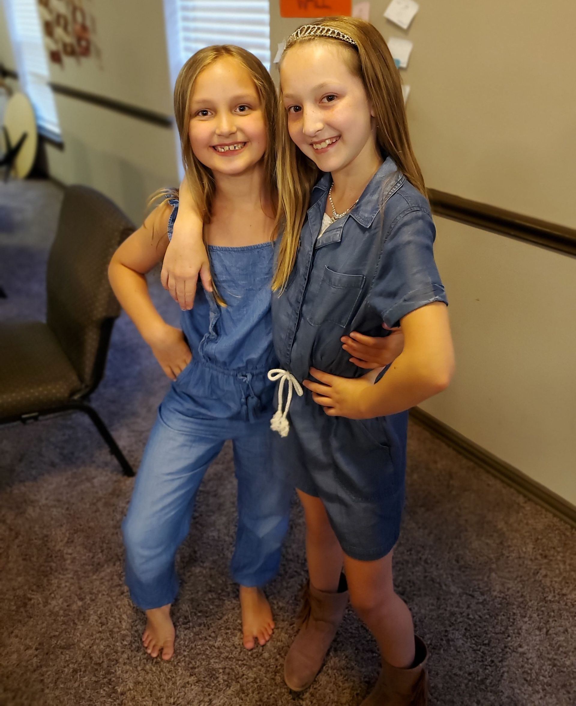 2 elementary aged girls side hugging and smiling at the camera