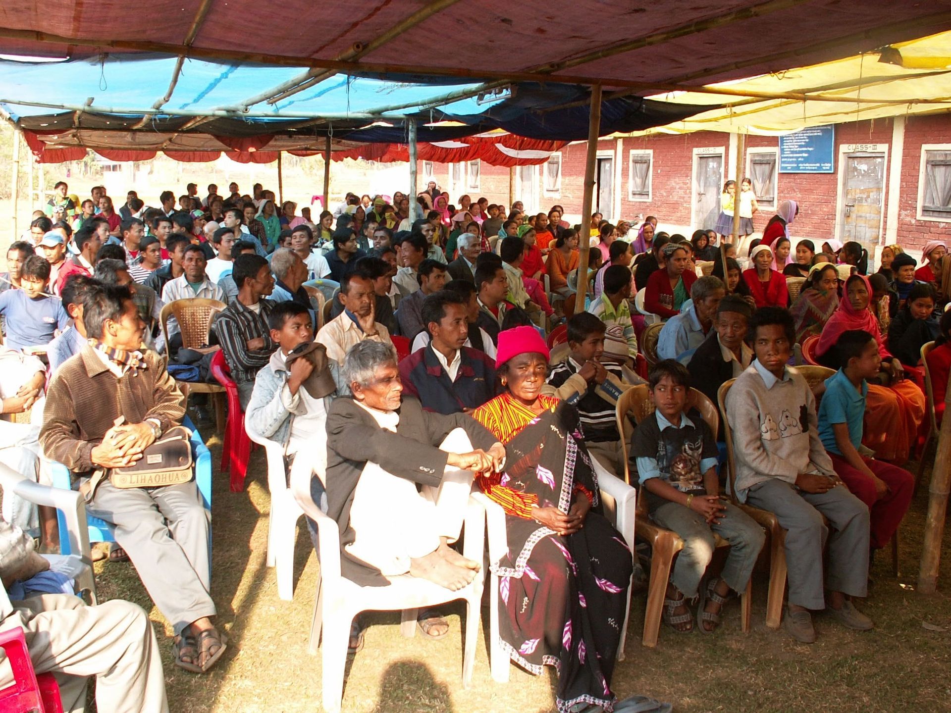 a crowd of South African residents seated under a tent listening to Pastor Gary of Citipointe Church preaching