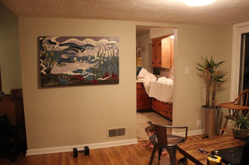 A living room with a large painting on the wall.