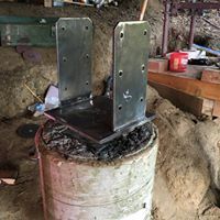 A metal bracket is sitting on top of a concrete cylinder.