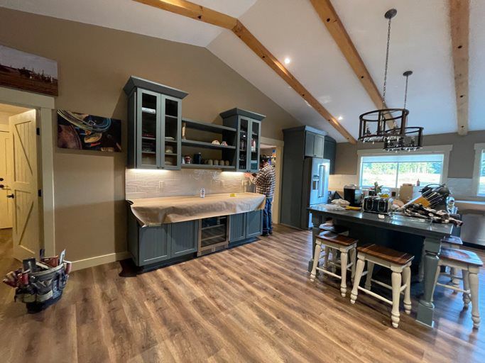 A kitchen with wooden floors , cabinets , stools and a large island.