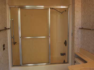 A bathroom with a sliding glass shower door and a bathtub.