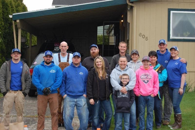 A group of people are posing for a picture in front of a house.