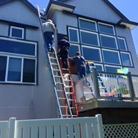 A group of people are standing on a ladder on the side of a house.