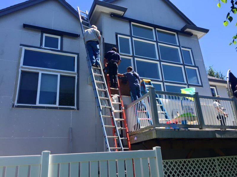 A group of men are painting the side of a house.