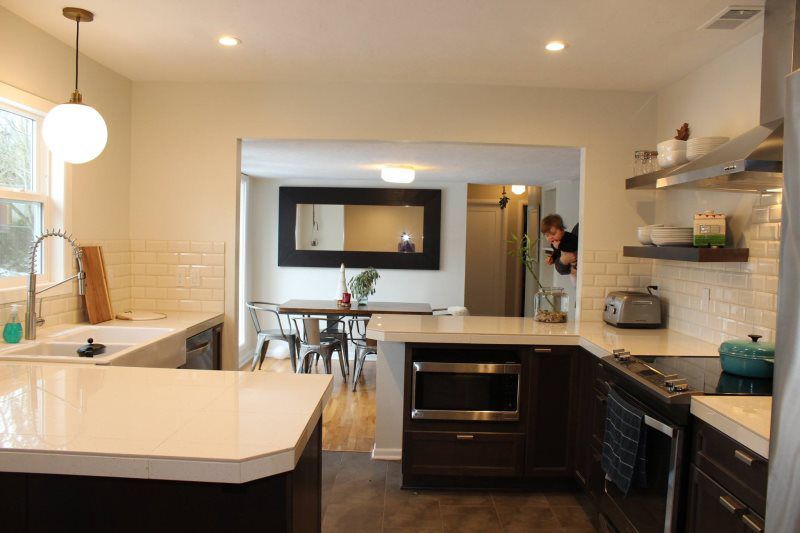 A man is taking a picture of a kitchen with a table and chairs in the background.