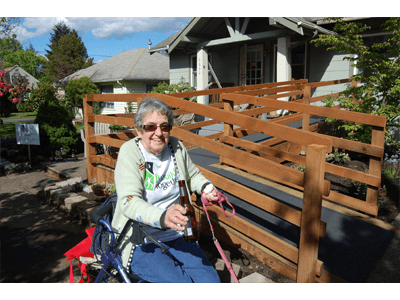 A woman in a wheelchair is sitting next to a wooden ramp holding a bottle of beer.