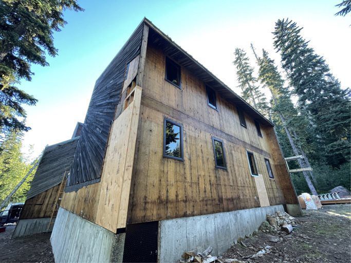 A large wooden house is being built in the woods.