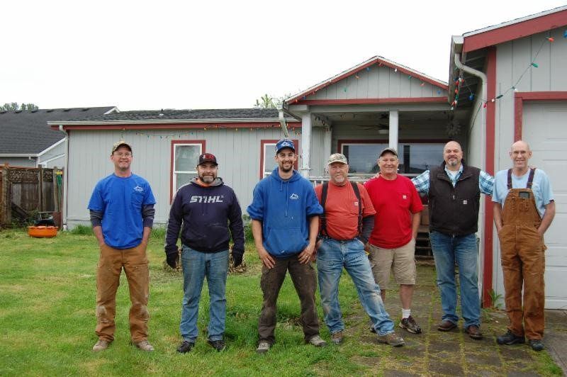 A group of men are posing for a picture in front of a house.
