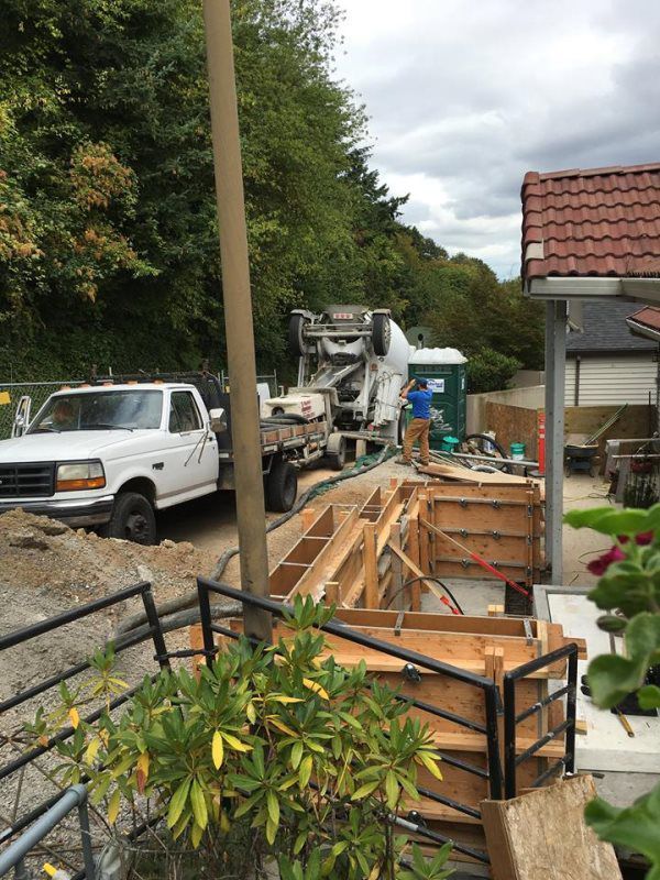 A white truck is parked next to a concrete mixer on a construction site.